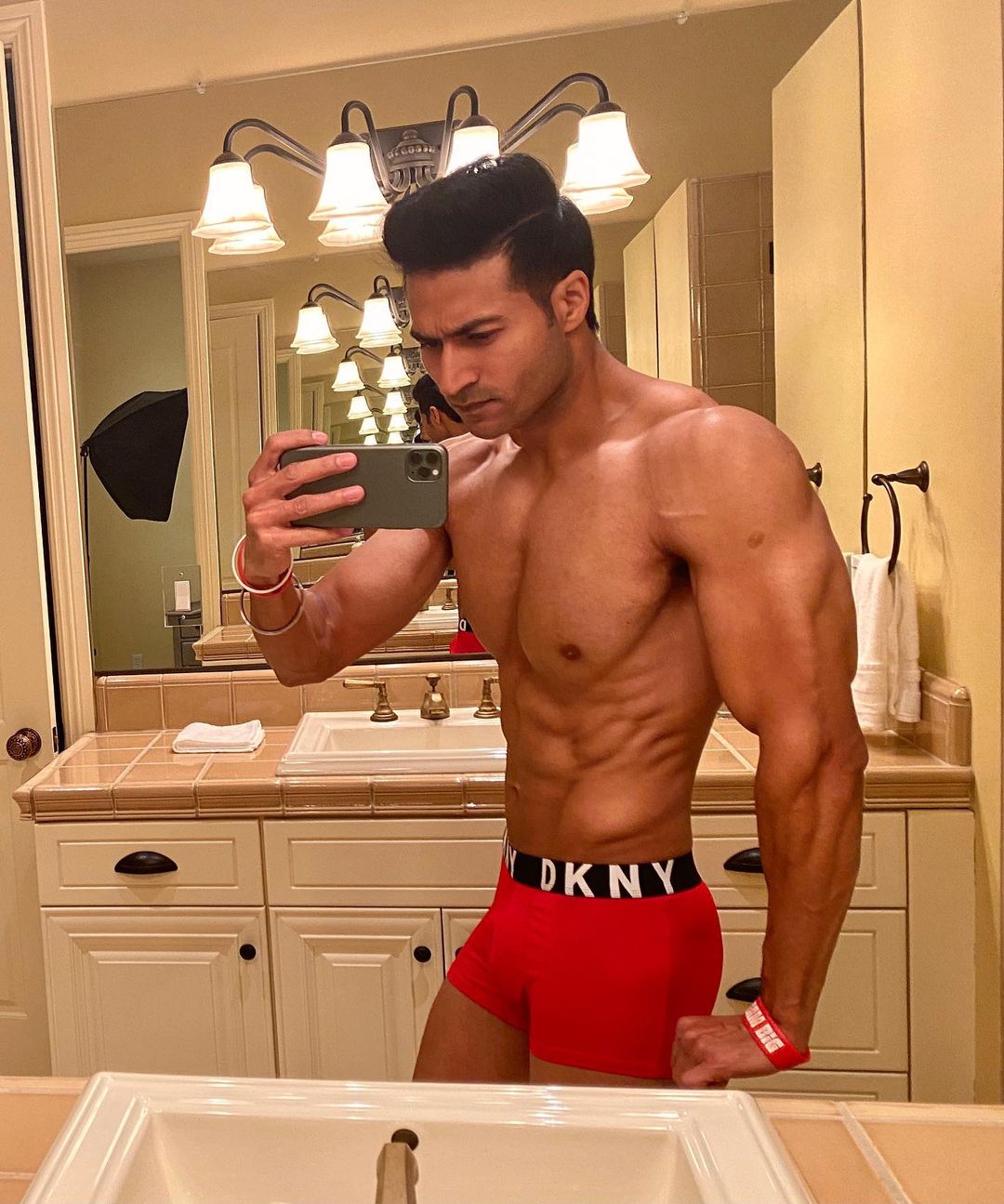 Guru Mann a Famous Health Influencer posing in his Chiselled Cut Body in Red Trunks Biographia